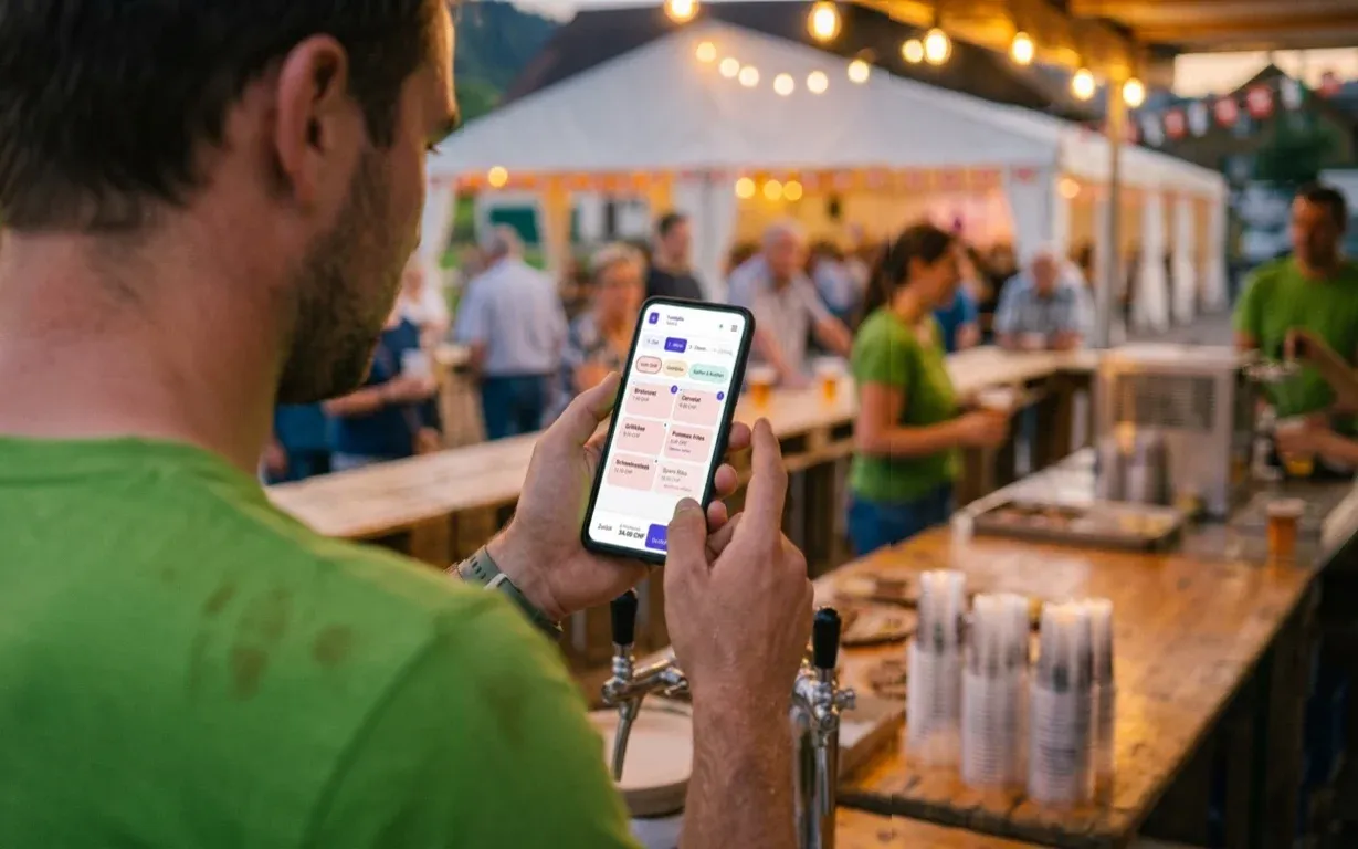 Helfer in grünem Vereins-T-Shirt tippt an der Festbar eine Bestellung ins Handy