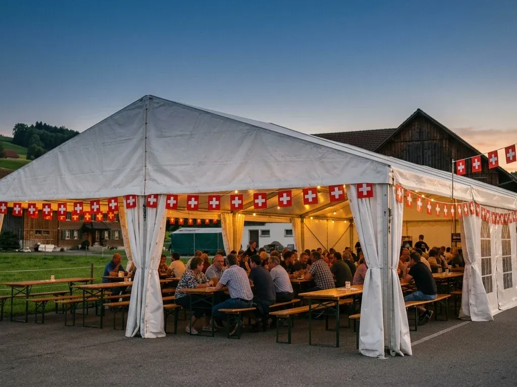 Voll besetztes Festzelt mit Schweizerfahnen in der Abenddämmerung